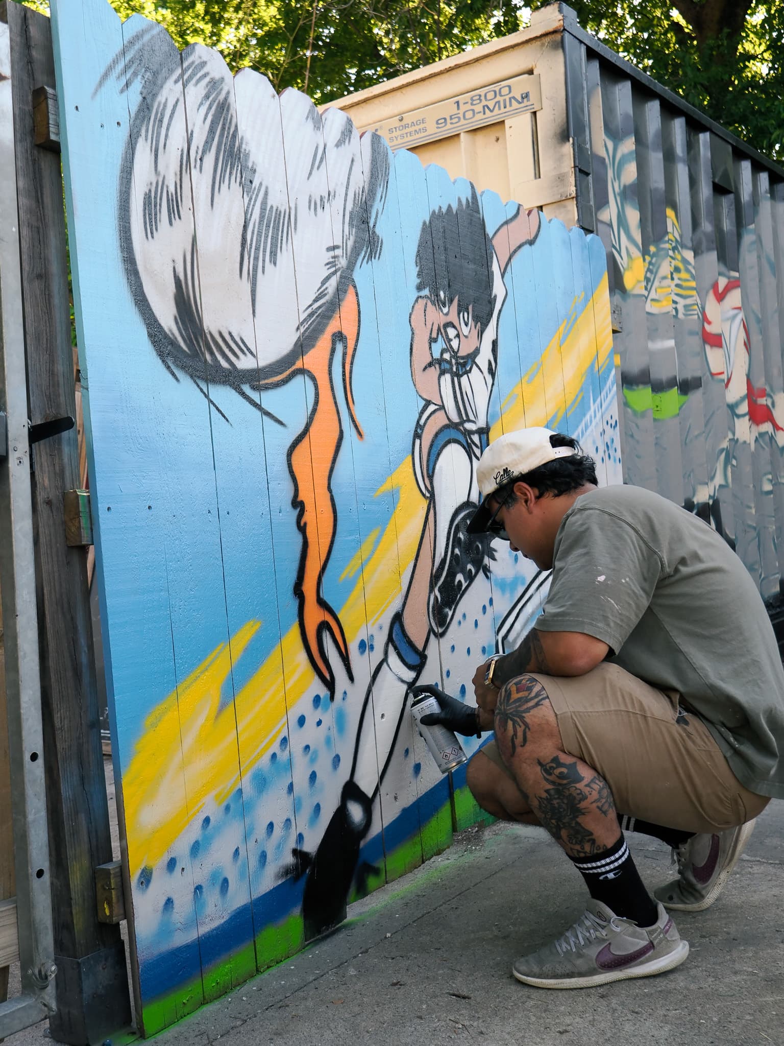 Artist painting a soccer-themed mural